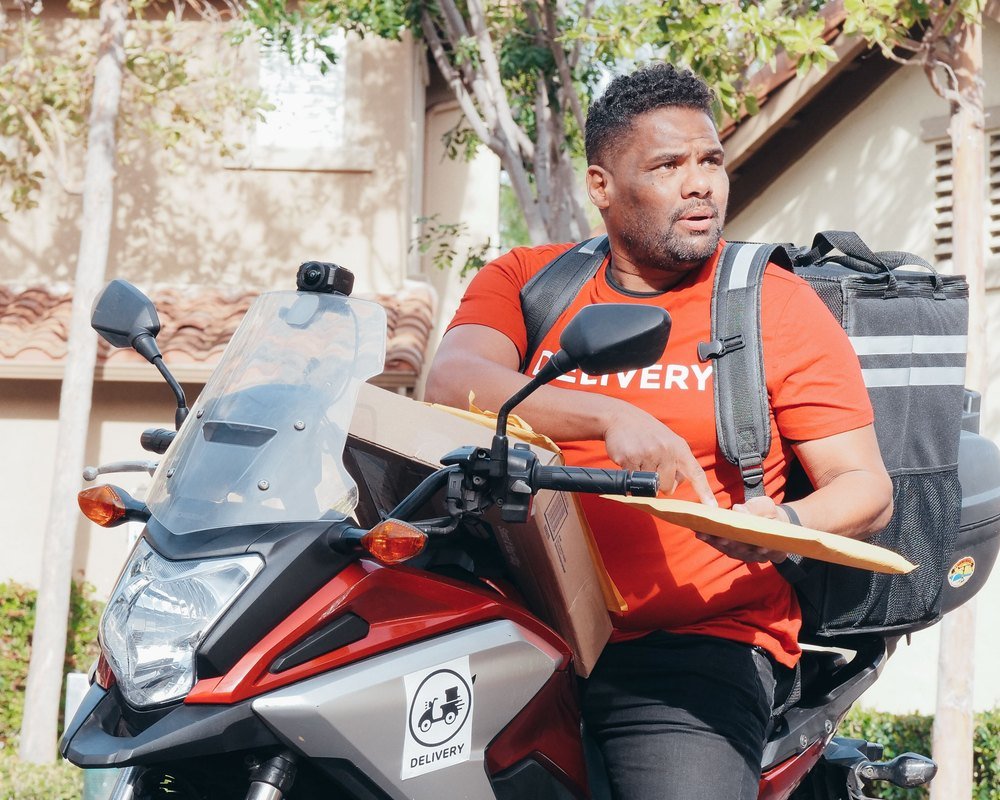 Entregador de moto com a bolsa térmica nas costas, pronto para sair para a entrega